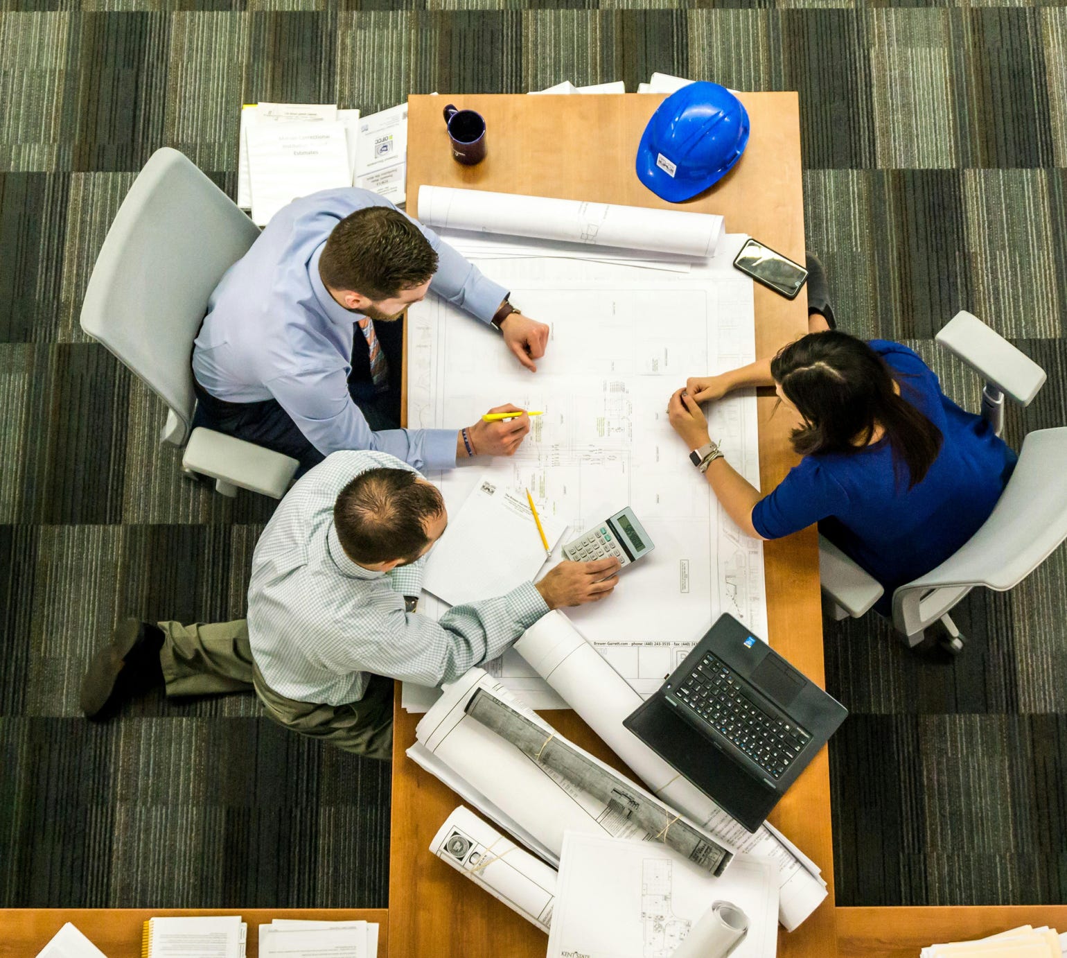 Top view of a team working on construction plans in an office setting.